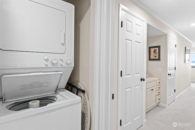 laundry area featuring crown molding, light colored carpet, and stacked washer and clothes dryer