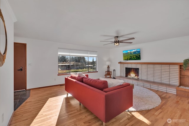 living room featuring a fireplace, light wood-type flooring, and ceiling fan