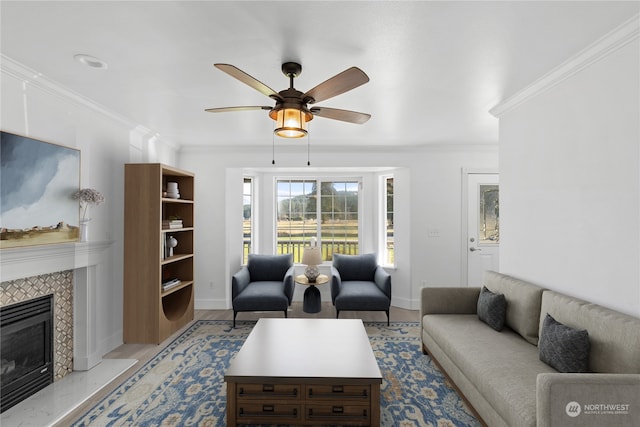 living room featuring crown molding, a fireplace, ceiling fan, and light wood-type flooring