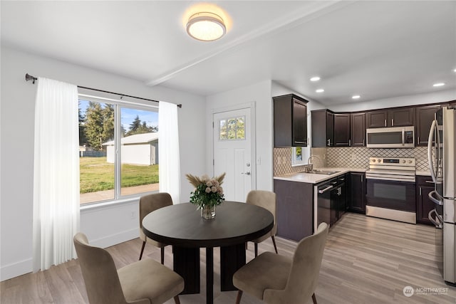 kitchen featuring tasteful backsplash, appliances with stainless steel finishes, sink, and light hardwood / wood-style flooring