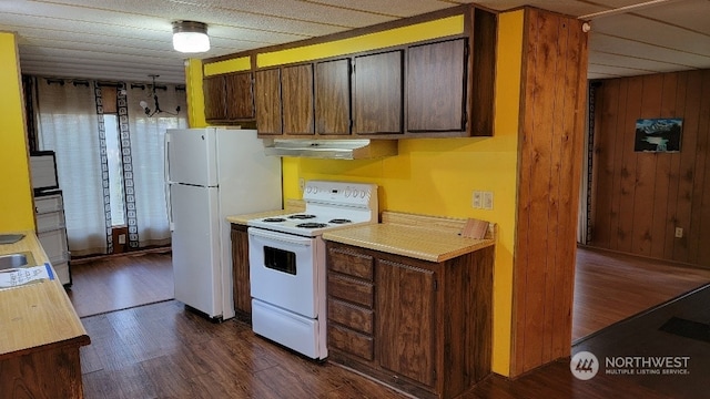 kitchen with white appliances, dark hardwood / wood-style floors, and wood walls