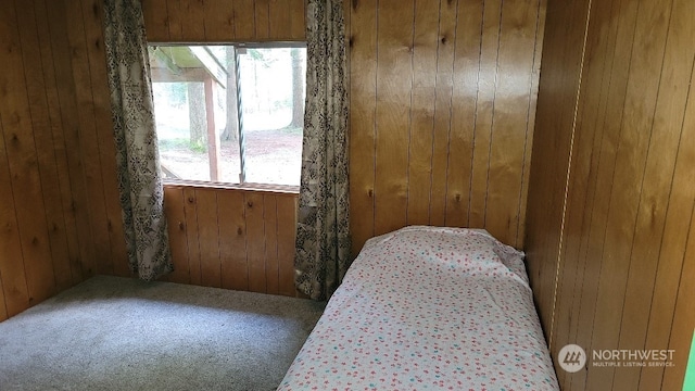 bedroom with carpet and wood walls