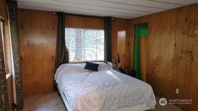 bedroom with carpet and wood walls