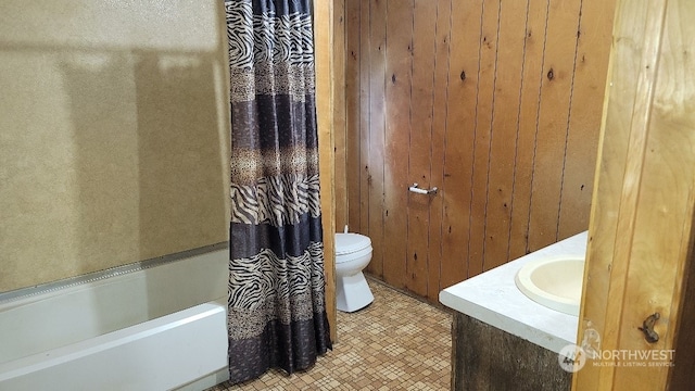 full bathroom featuring wood walls, sink, tile patterned flooring, toilet, and shower / bath combo with shower curtain