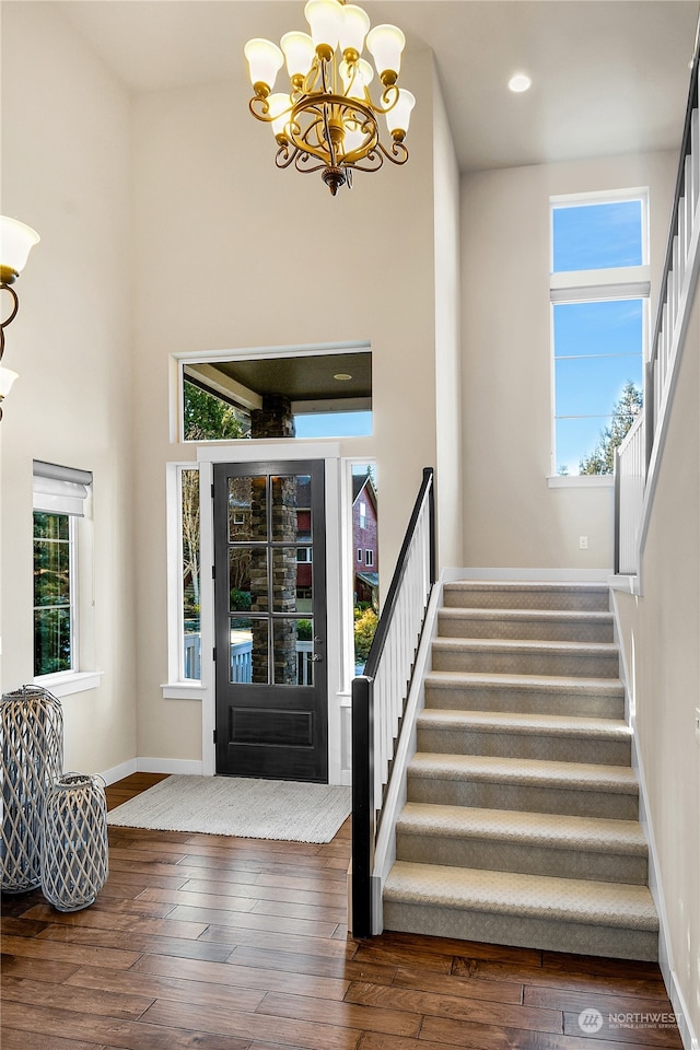 foyer featuring dark hardwood / wood-style flooring, a notable chandelier, and a towering ceiling