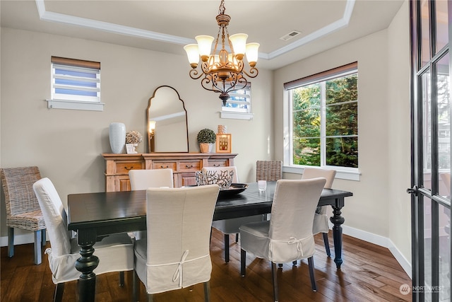 dining room with crown molding, a tray ceiling, dark hardwood / wood-style flooring, and a chandelier