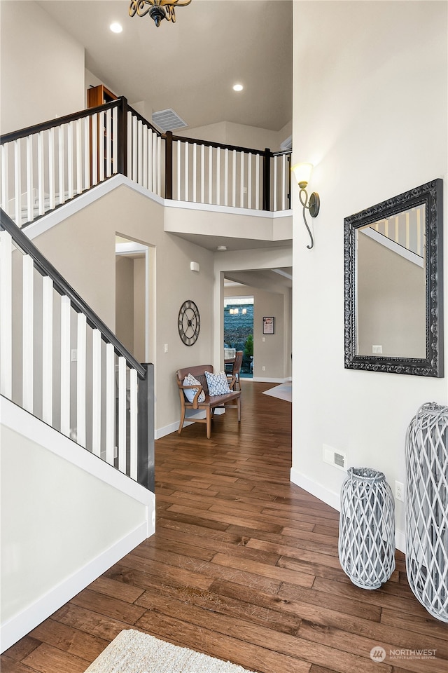 foyer entrance with hardwood / wood-style floors and high vaulted ceiling