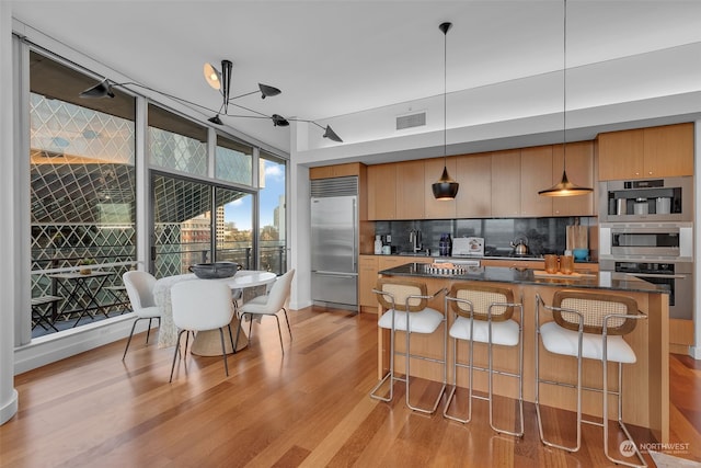 kitchen featuring decorative light fixtures, stainless steel appliances, tasteful backsplash, sink, and a breakfast bar area