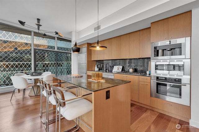 kitchen featuring a kitchen island, decorative light fixtures, light hardwood / wood-style floors, floor to ceiling windows, and a breakfast bar