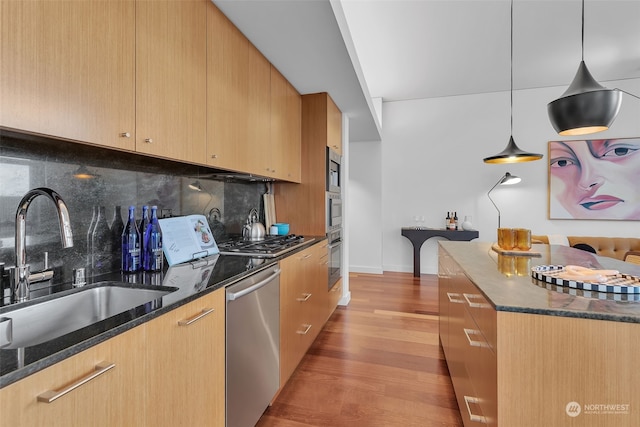 kitchen featuring decorative light fixtures, dark stone counters, sink, and stainless steel appliances