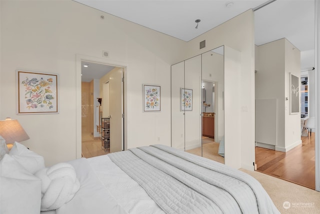 carpeted bedroom featuring a closet, ensuite bathroom, and lofted ceiling