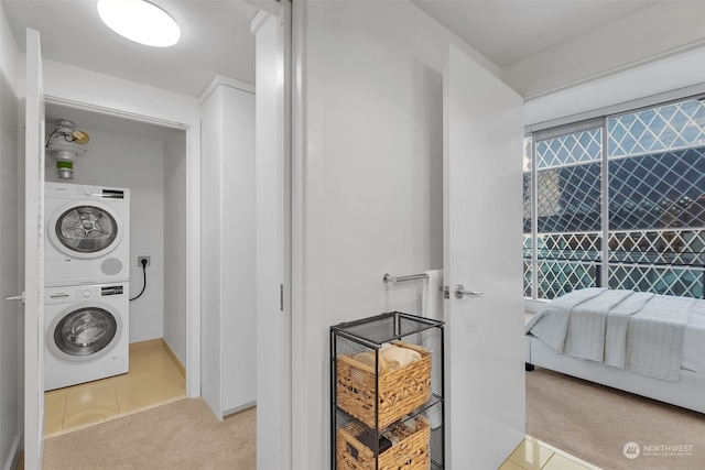 laundry area featuring light carpet and stacked washer / dryer