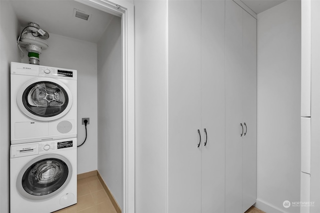 laundry area featuring stacked washer and clothes dryer and light tile patterned flooring