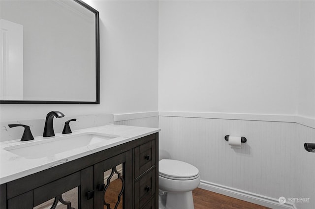 bathroom with hardwood / wood-style floors, toilet, and vanity