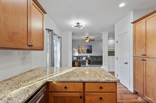 kitchen with ornate columns, ceiling fan, tasteful backsplash, light stone countertops, and light hardwood / wood-style flooring