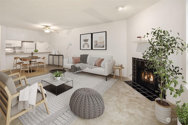 carpeted living room with a fireplace and ceiling fan