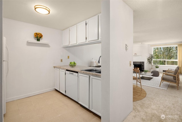 kitchen with white cabinetry, dishwasher, sink, and a fireplace