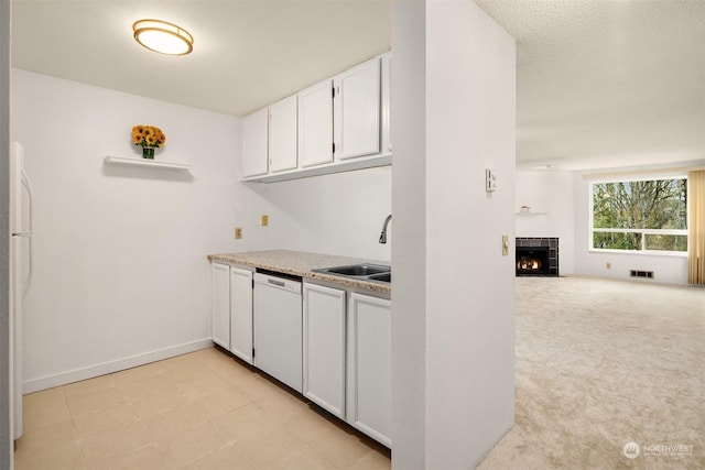 kitchen featuring white appliances, a fireplace, sink, and white cabinets