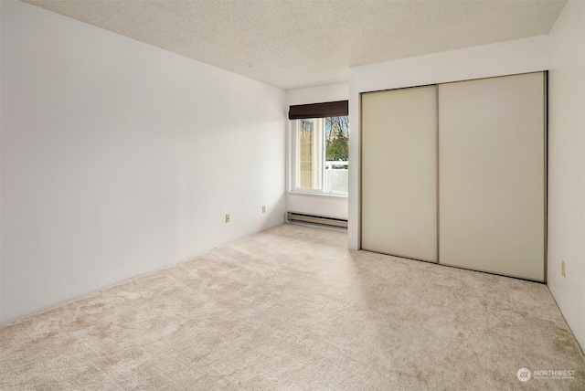 unfurnished bedroom featuring a baseboard radiator, light carpet, a textured ceiling, and a closet