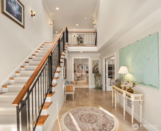 foyer featuring baseboards, recessed lighting, stairs, a towering ceiling, and crown molding