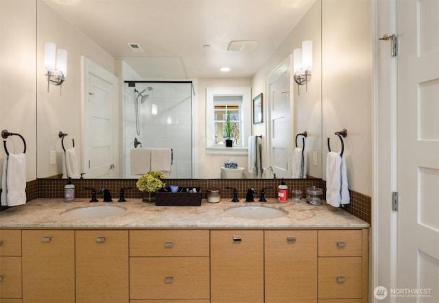 full bathroom with double vanity, visible vents, a shower stall, and a sink