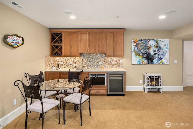 kitchen with beverage cooler, visible vents, tasteful backsplash, and oven