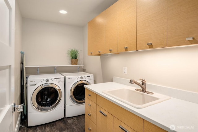 clothes washing area with washing machine and clothes dryer, a sink, recessed lighting, cabinet space, and dark wood-style flooring