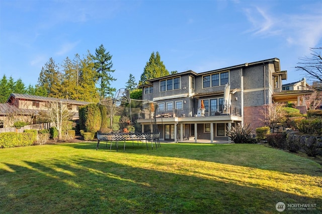 back of property featuring a patio, a trampoline, and a lawn