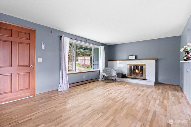 unfurnished living room featuring a baseboard heating unit, light hardwood / wood-style floors, and a fireplace