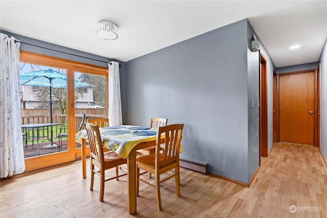 dining area with light wood-type flooring and a baseboard heating unit