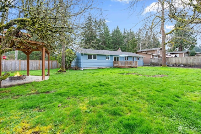 back of house featuring a deck, a yard, and a fire pit