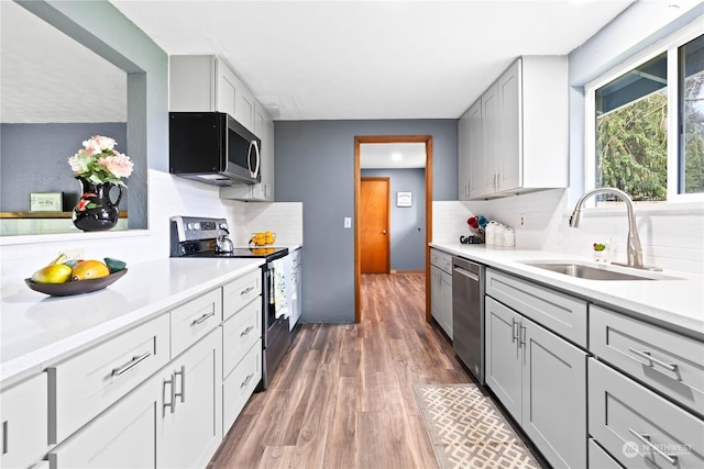 kitchen with dark wood-type flooring, appliances with stainless steel finishes, backsplash, and sink