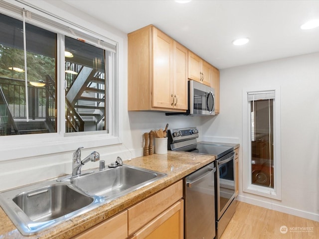 kitchen featuring appliances with stainless steel finishes, light brown cabinetry, light hardwood / wood-style flooring, and sink