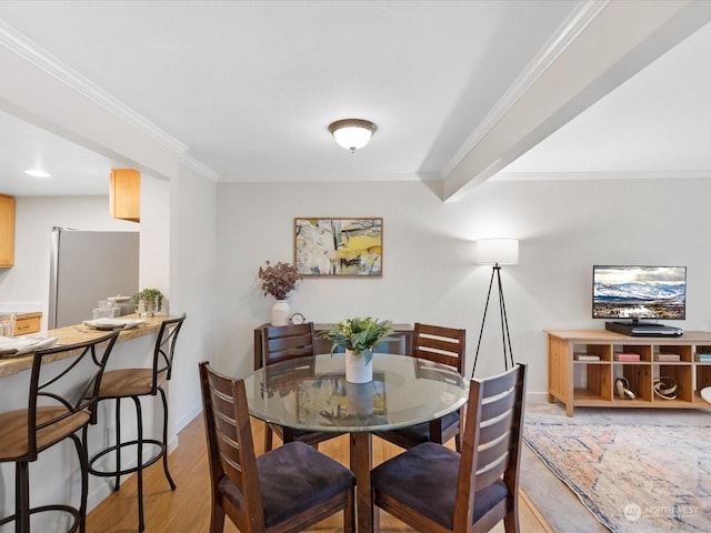 dining area featuring ornamental molding and light hardwood / wood-style flooring