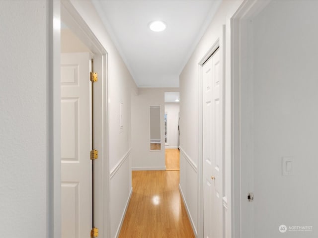 hallway featuring light wood-type flooring and ornamental molding