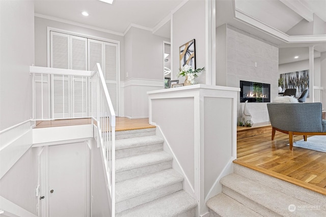 stairway with crown molding, a fireplace, and hardwood / wood-style floors