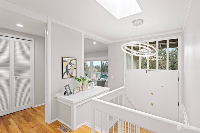 interior space featuring ornamental molding, a skylight, and light hardwood / wood-style floors