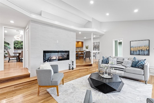 living room with a fireplace, vaulted ceiling, and hardwood / wood-style floors