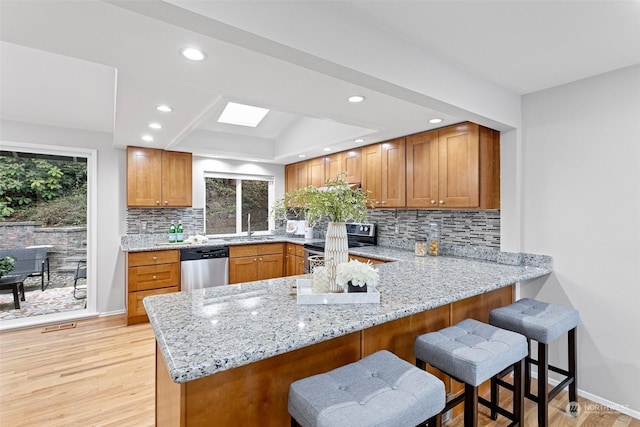 kitchen with light stone counters, appliances with stainless steel finishes, a kitchen bar, and kitchen peninsula