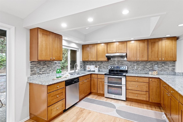 kitchen with lofted ceiling, sink, light hardwood / wood-style flooring, appliances with stainless steel finishes, and light stone countertops