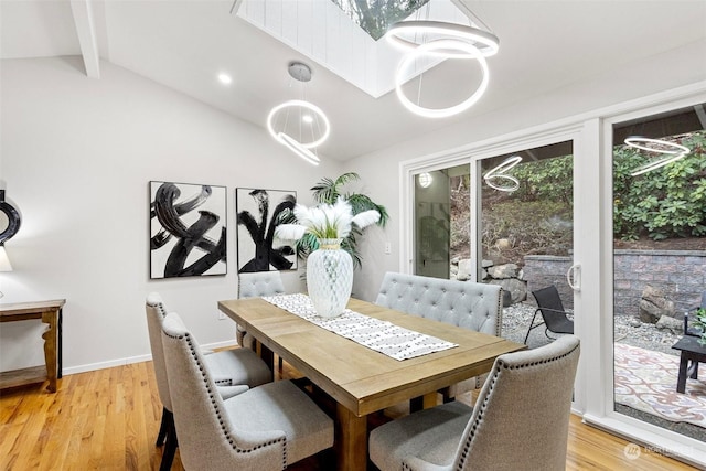 dining room with lofted ceiling with beams and light wood-type flooring