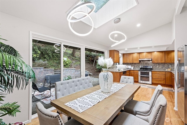 dining area featuring high vaulted ceiling and light hardwood / wood-style floors