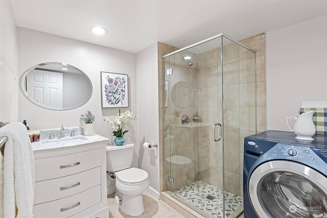 bathroom featuring tile patterned floors, toilet, a shower with shower door, vanity, and washer / clothes dryer