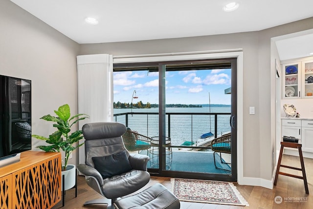 sitting room with a water view and light hardwood / wood-style flooring