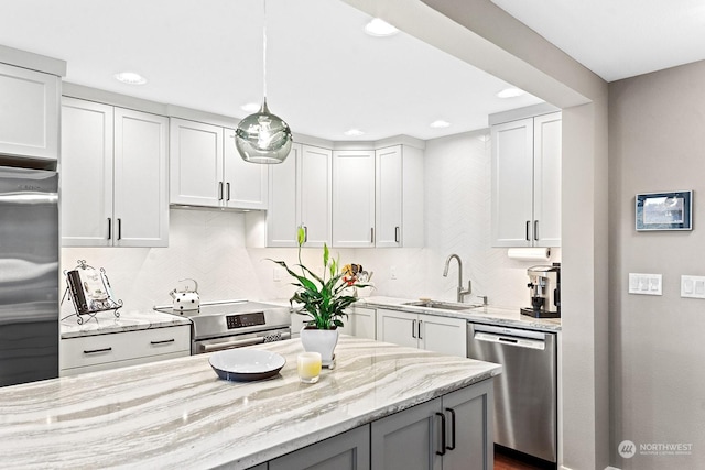 kitchen featuring sink, appliances with stainless steel finishes, light stone countertops, decorative backsplash, and decorative light fixtures