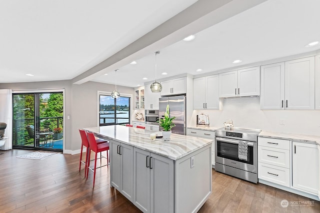 kitchen featuring appliances with stainless steel finishes, hanging light fixtures, light stone counters, white cabinets, and a kitchen island