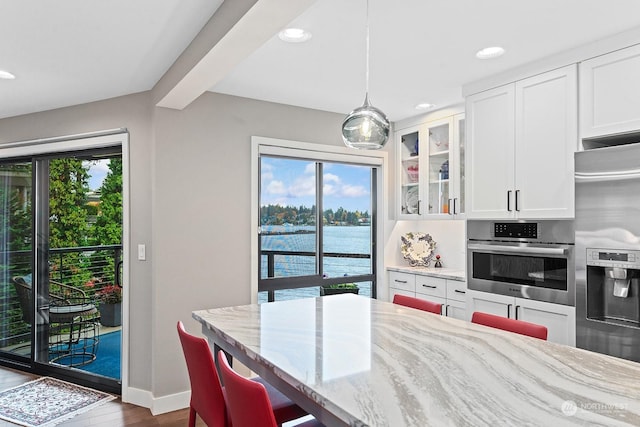 dining room with hardwood / wood-style floors, beamed ceiling, and a water view