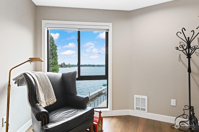 sitting room with a water view and hardwood / wood-style floors