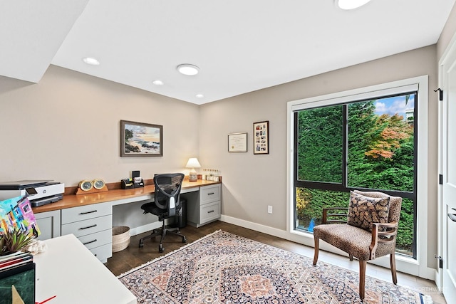 office with dark wood-type flooring and built in desk