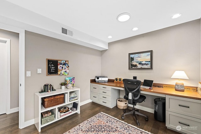 office space with built in desk and dark wood-type flooring